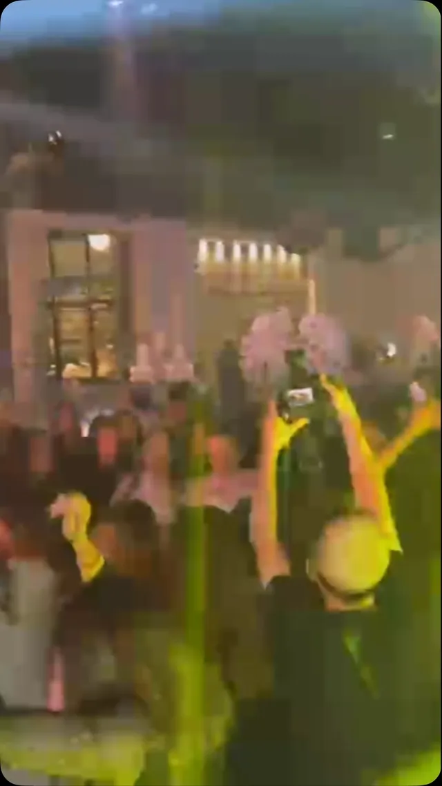אורחים מרימים ידיים ומצלמים ברחבת אירוע מוארת